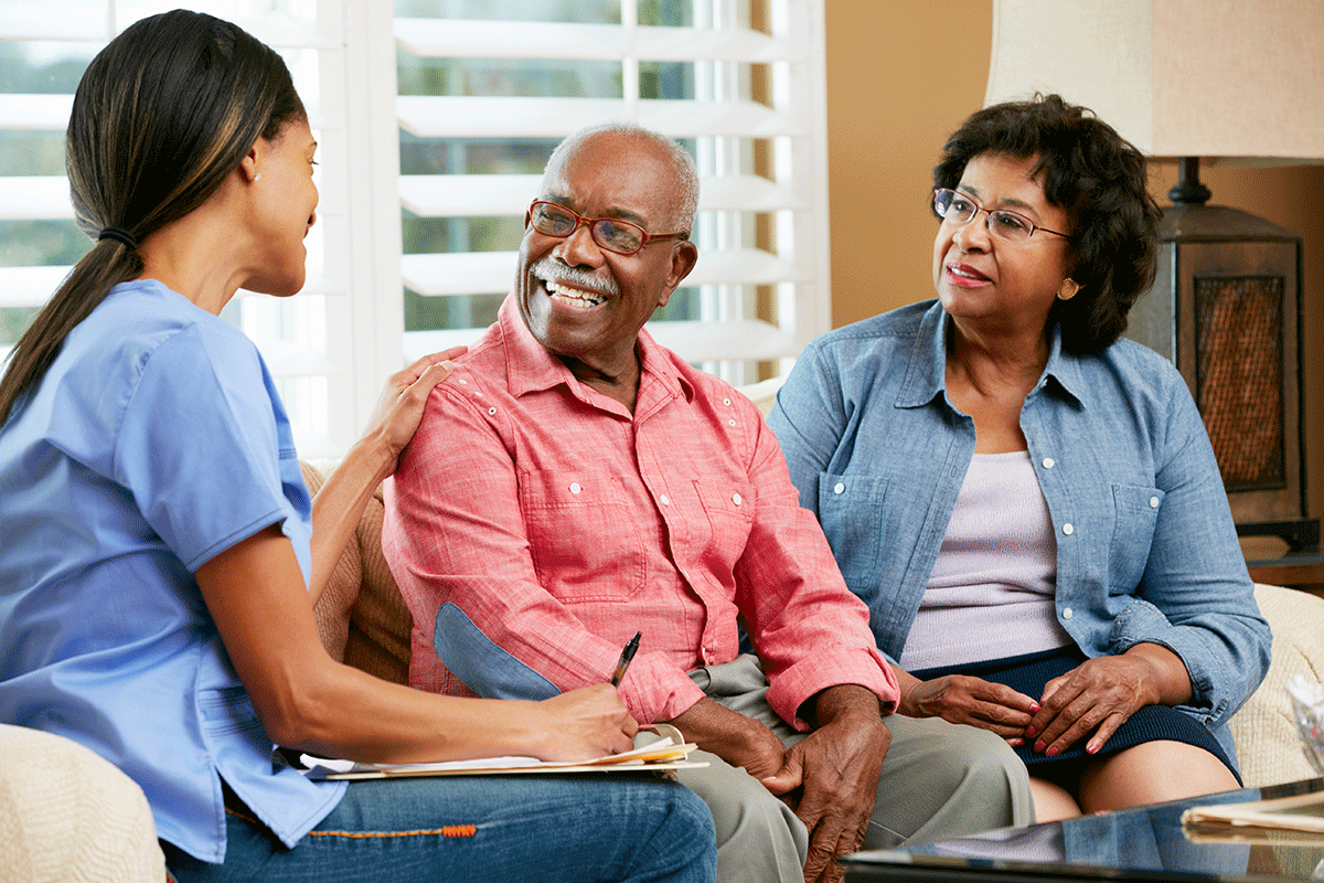 Caregiver sitting with a senior couple, listening during a calm family conversation
